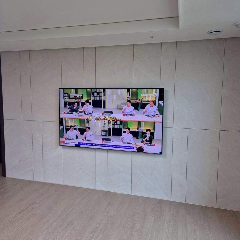 금천구에서 98인치 안전하중과 대형거치을 진행하며 좌우 여백과 하단 높이를 기준으로 화면 중심을 표시한 사진입니다. 소파에서 바라보는 시선과 거실장 폭을 함께 비교해 높이와 좌우 위치를 결정했습니다